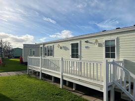 A mobile home with a deck and grassy area at Gainc Bach in Abergele