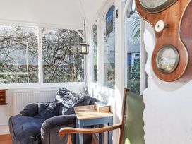 A conservatory with an armchair and table at Rosedale in St. Ives