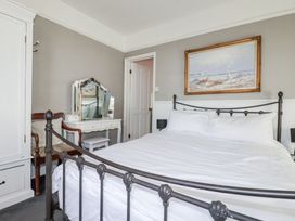 A bedroom with a bed, mirrors, a wardrobe, and a painting at Rosedale in St. Ives