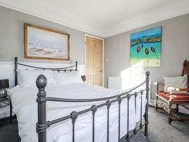 A bedroom with a bed and paintings at Rosedale in St. Ives