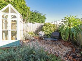 A garden with a greenhouse, benches, and plants at Rosedale in St. Ives