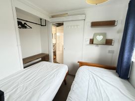 A bedroom with two beds and a wooden table at 300 California Sands, California, Norfolk