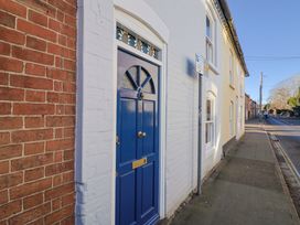 A blue front door next to a brick wall at Rope Cottage in Bridport