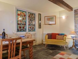 A living room with a dining table and stained glass windows at Rope Cottage in Bridport