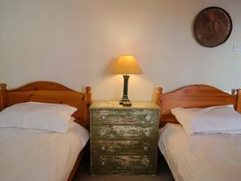 A bedroom with two beds and a green chest of drawers at Rope Cottage in Bridport