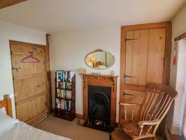 A bedroom with a bed, bookshelf, fireplace, and rocking chair at Rope Cottage in Bridport