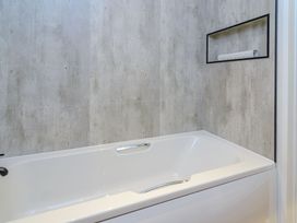 A bathtub with a shelf on the wall at The Castor in Kings Cliffe