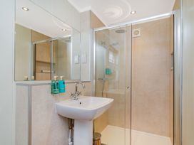 A bathroom with a shower, sink, and mirror at The Kingscliffe (Pet) Kings Cliffe