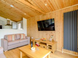A living room with a sofa, television, and coffee table at The Sutton in Kings Cliffe