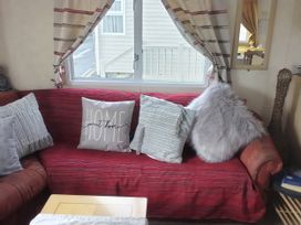 A couch with pillows and a window at No. 30 First Avenue in Rhyl