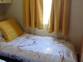 A bed with a yellow pillow and curtains at No. 30 First Avenue in Rhyl
