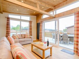A living room with a sofa, coffee table, and large windows at The Wansford in Kings Cliffe