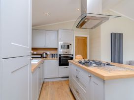 A kitchen with cabinets and an island showing an oven and stove at The Ailsworth (Pet) Kings Cliffe