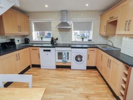 A kitchen with appliances and wooden cabinets at Beadlin cottage Beadnell