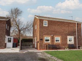 A brick house with benches in the outdoor area at Beadlin cottage Beadnell