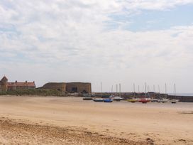 A beach with boats moored at a pier at Beadlin cottage in Beadnell