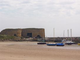 Boats near a stone building and pier at Beadlin cottage Beadnell