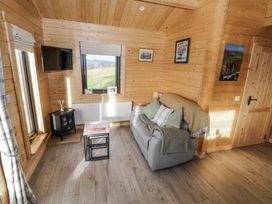 A living room with a sofa and television at Glenview Log Cabin Ballycastle