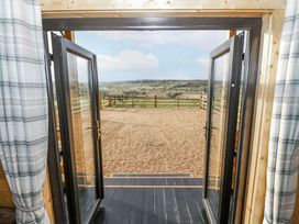 Double doors leading to a gravel area with a fenced landscape at Glenview Log Cabin in Ballycastle