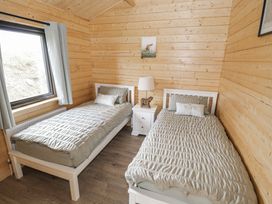 A bedroom with two beds and a bedside table at Glenview Log Cabin Ballycastle