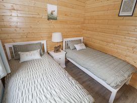 A bedroom with two beds and a nightstand at Glenview Log Cabin in Ballycastle