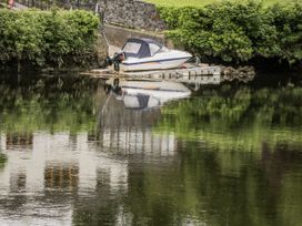 A boat moored by a dock reflecting on water at Glenview Log Cabin Ballycastle