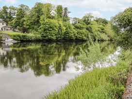 A river with trees and a house by the shore at Glenview Log Cabin in Ballycastle