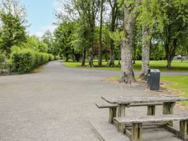 A park with a pathway, trees, and a bench at Glenview Log Cabin in Ballycastle