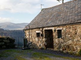 A stone cottage exterior with basketball hoop and gate at Ty Uchaf in Colwyn Bay