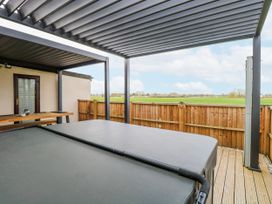 An outdoor area with a hot tub and wooden decking at Aloe Lodge in Banham