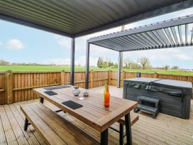 An outdoor patio with a table and hot tub at Aloe Lodge in Banham