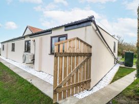 An exterior view of a house with an air conditioning unit and wooden fence at Aloe Lodge Banham
