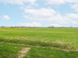 A green field with trees and clouds at Aloe Lodge in Banham