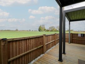 An outdoor area with wooden decking and a view of grass fields at Aloe Lodge in Banham