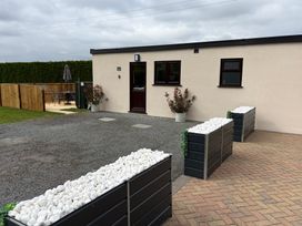 An outdoor area with a house, gravel driveway, table, chairs, and planters at Aloe Lodge in Banham