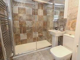 A bathroom with a shower, washbasin, towel radiator and toilet at Crantock