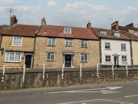 A row of houses with a stone wall and street in front at Crantock