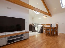 A dining area with a television and kitchen at The Maisonette in Hayle