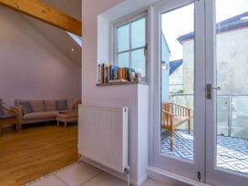 A living room with a sofa and books on a shelf at The Maisonette in Hayle