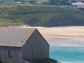 A beach view with a building and hills at The Maisonette in Hayle