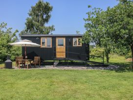 A black shed with windows and a ramp along with a table and chairs at Dave's Place in Broadstone near Munslow