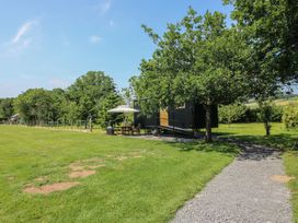 An outdoor area with a cabin and seating under an umbrella at Dave’s Place Broadstone near Munslow