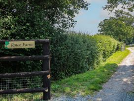 A sign for Rowe Farm next to a gravel path surrounded by hedges near Broadstone near Munslow