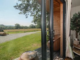 A view from a cabin door with a chair and table at Leafy Oaks Cabin in Munslow