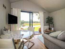 A living room with a dining table and television at Leafy Oaks Cabin in Munslow