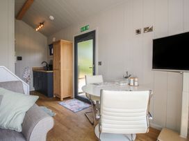 A living room with a sofa and dining area at Leafy Oaks Cabin in Munslow