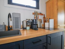 A kitchen with a sink and various appliances at Leafy Oaks Cabin Munslow