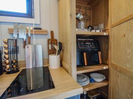 A kitchen with a countertop, knives, air fryer, and plates at Leafy Oaks Cabin in Munslow