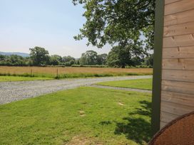 A view of a grassy field with trees and a gravel path at Leafy Oaks Cabin in Munslow