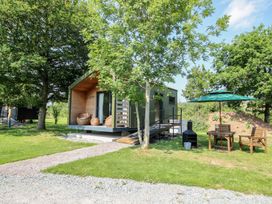 A cabin with chairs and a table in the garden at Leafy Oaks Cabin in Munslow
